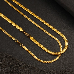 Close-up of three golden flat snake bone chains in stainless steel on black background