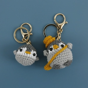 Handmade crochet penguin keychains in grey and white with cute yellow hat and accessories