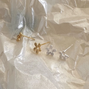 Macro detail of minimalist 925 sterling silver floral stud earrings in gold and silver