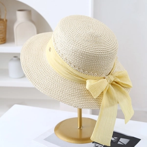 Detail of straw hat with delicate lace ribbon bow and golden emblem on display