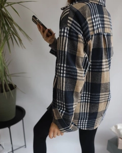 Detail of oversized plaid shacket showing navy and khaki flannel texture and draped fit