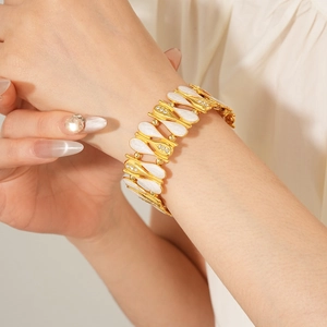Close-up of vintage gold bracelet with white enamel teardrops and sparkling zircons