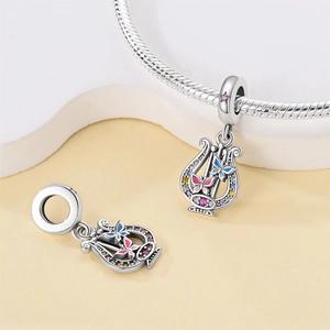 Macro detail of silver harp charm with enamel butterflies and colorful zircon stones