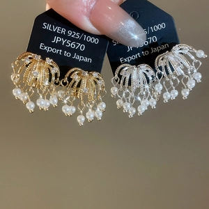 Detailed view of fireworks-inspired zircon and pearl drop clip earrings