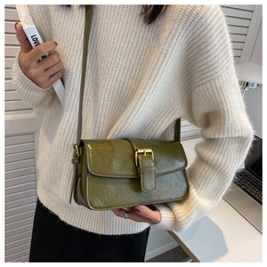 Detail of vintage olive green waxed leather crossbody bag with golden buckle closure