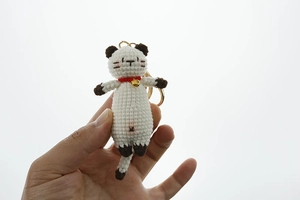 Handheld view of handmade crochet Siamese cat keychain with gold bell and red collar