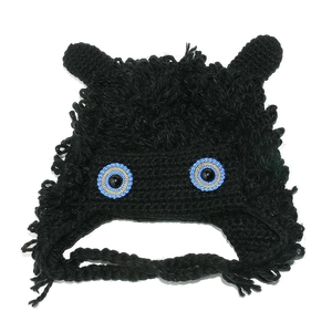 Detail of handmade black crochet monster hat with large blue eyes and knit earflaps