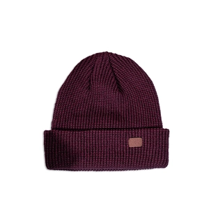 Detailed view of the thick ribbed knit texture and brown leather label on the burgundy beanie