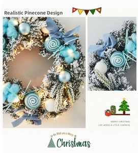 Detail of Christmas wreath with blue ornaments, frosted pine needles, and LED warm lights