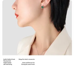 Close-up of model wearing a green heart-shaped earring made of 18k gold-plated titanium steel