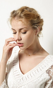Close-up of a gold heart pendant necklace on a model with white lace blouse
