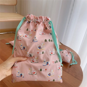 Detail of pink cotton drawstring bag with cartoon duck prints and green ribbons