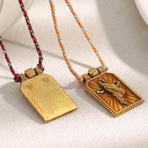 Detail of 18K gold plated rectangular pendants with enamel cross and woven cord