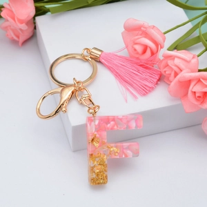 Detail of pink resin letter F keychain with gold foil flakes and matching tassel