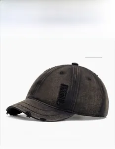 Close-up of black washed distressed denim baseball cap with short brim and torn details