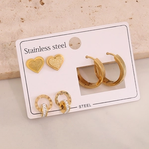 Close-up of gold stainless steel earring set with heart, hoop, and Roman numeral designs