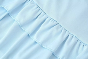 Detail shot of light blue fabric featuring ruffled edges and professional overlock stitching