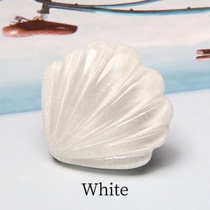 Détail d'un accessoire en résine en forme de coquillage blanc avec fini pailleté nacré