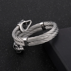 Detailed macro view of dual skull heads and twisted steel cable on a men's bangle