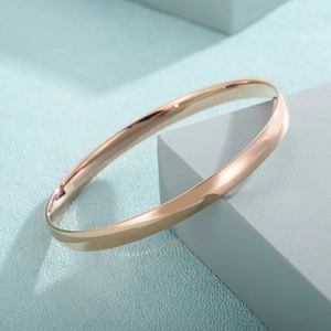 Close-up of polished rose gold titanium bracelet with a mirror finish on a blue stand