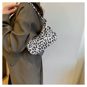 Gros plan du sac baguette imprimé léopard porté avec un trench-coat marron