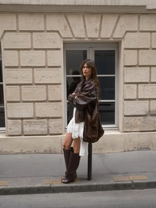 Tenue de rue élégante montrant une robe en dentelle blanche avec veste en cuir et bottes