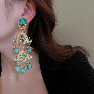 Détail de boucles d'oreilles vintage dorées avec résine sarcelle et cristaux bleus