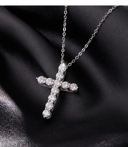 Macro shot of silver S925 cross pendant with sparkling moissanite stones on black fabric