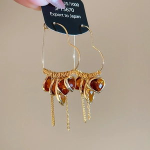Detail of 18K gold-plated heart hoop earrings with amber crystals and fine tassels