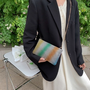 Rainbow rhinestone crossbody bag with gold chain strap shown in an outdoor setting