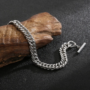 Close-up of silver titanium steel curb chain bracelet with toggle clasp on wood