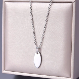 Close-up of polished silver oval pendant and chain on elegant satin jewelry display box