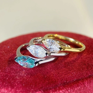 Macro shot of three marquise cut rings with blue and white stones on red velvet