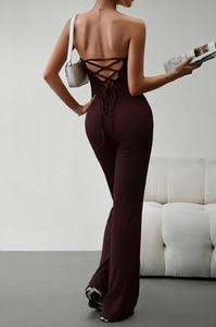 Detail of slim-fit brown jumpsuit showing the open back design and lace-up straps