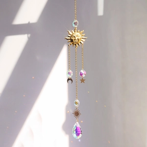Golden sun moon crystal suncatcher casting rainbow prism light on a white wall