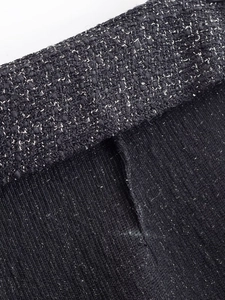 Close-up detail showing the black tweed weave texture and vertical stripe fabric stitching