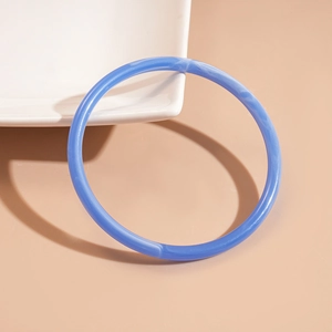 Macro detail of blue marbled acrylic bangle resting on white ceramic bowl edge