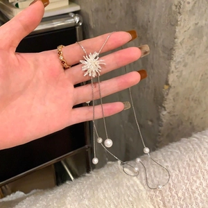 Élégant collier argenté avec pendentif étoile et perles blanches sur fond texturé gris