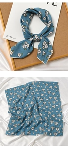 Close-up of light blue floral scarf with delicate white flower patterns and silk texture