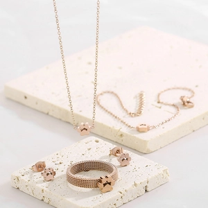 Rose gold stainless steel cat paw jewelry set with mesh ring on textured stone pedestal