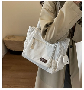Detailed shot of white corduroy tote bag showing side pockets and textured fabric