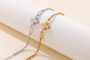 Detail of vintage gold and silver stainless steel cross bracelets on a white display