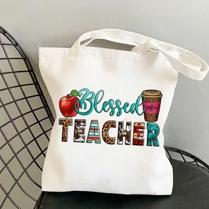 Blessed Teacher white canvas tote bag with leopard print graphics on a black chair