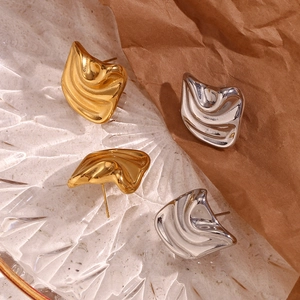 Modern irregular wave earrings in gold and silver finish on textured glass plate