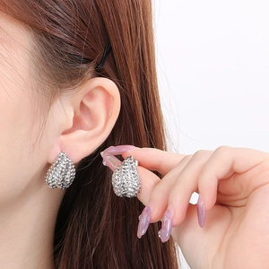 Close-up of silver-tone teardrop earrings with textured granules on a model's ear