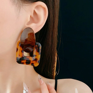 Detail view of retro geometric resin earrings with tortoiseshell pattern on model
