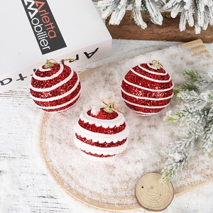 Close-up of red and white glitter Christmas ball ornaments on snowy wooden tray