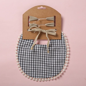 Détail du bavoir bébé en vichy avec dentelle et barrettes assorties sur carton