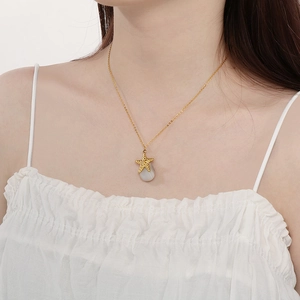 Detail of a gold starfish and grey stone pendant necklace worn on a female model's neck