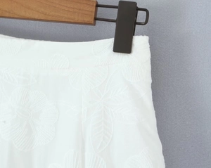 Détail de la broderie florale et de la fermeture éclair invisible sur la jupe blanche